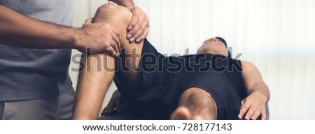 Therapist treating injured knee of athlete male patient - sport physical therapy concept, panoramic web banner