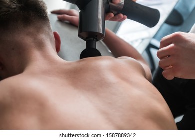 Therapist Treating Injury Of Professional Athlete Male Patient. Black Massage Gun, Used By Professionals To Massage The Body.Sport Physical Therapy Concept. - Photography