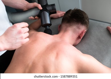 Therapist Treating Injury Of Professional Athlete Male Patient. Black Massage Gun, Used By Professionals To Massage The Body.Sport Physical Therapy Concept. - Photography