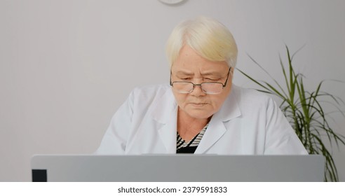 Therapist typing on laptop makes research taking notes on paper checklists. Senior nurse cheking histories of curent ill visitors. - Powered by Shutterstock