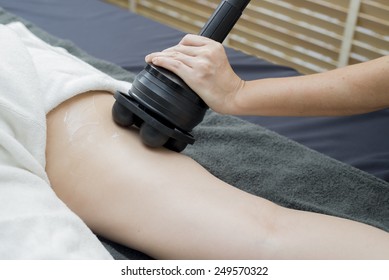 Therapist using tool for fat burning Massage on client's leg in spa