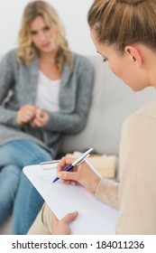 Therapist Writing Notes On Her Clipboard At Therapy Session