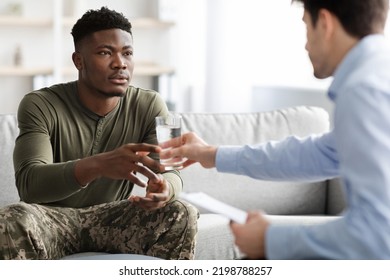 Therapist Young Man In Formal Outwear Passing Glass Of Water To His Stressful Emotional Patient Young African American Military Man Or Veteran While Having Conversation At Clinic