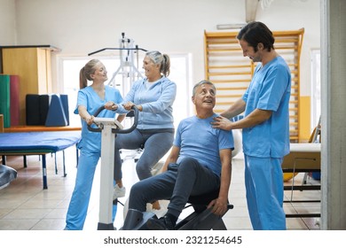 Therapists assisting happy senior man and woman exercising in rehabilitation center - Powered by Shutterstock