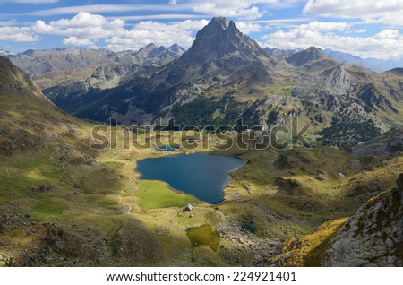 There are the alpine lake Gentau, the recognizable summit du Midi d'Ossau and remote mountain ranges in the panoramic view of the Bearn Pyrenees.