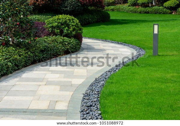 There is a black\
stone garden on the edge of the curved path, and the landscape lamp\
is on the green lawn. 