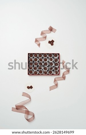 There is a box of individually packaged chocolate and a ribbon around it