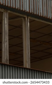 There is a building that features a considerable amount of windows alongside a wellused, rusty metal roof that adds character to its appearance