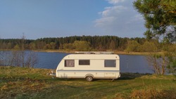 There Is A Caravan Trailer On The River Bank For A Comfortable Stay In The Spring For The Fishing Period. There Is A Forest Growing On The Banks Of The River.