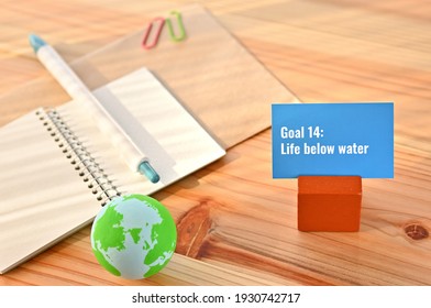 There Is Card With The Statement Goal 14:Life Below Water On It One Of The Goals Of The SDGs With Earth Ball.