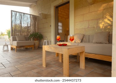 There is a charming outdoor patio featuring a comfortable couch along with a table that holds two elegant glasses filled with wine - Powered by Shutterstock