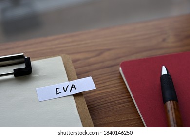 There Is A Clipborad, A Pen, And A Notebook With A Sticky Note Stuck To It That Says EVA Written On It. It Was An Abbreviation For Economic Value Added.