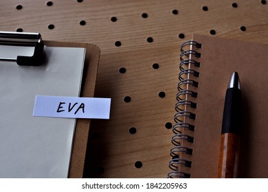 There Is A Clipborad, A Pen, And A Notebook With A Sticky Note Stuck To It That Says EVA Written On It. It Was An Abbreviation For Economic Value Added.