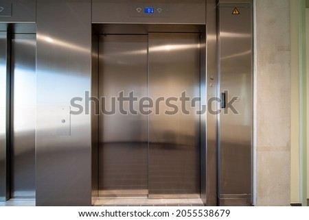 There is an elevator in the corridor of a large building