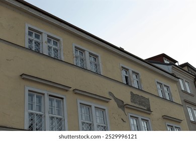 There exists a considerably large structure featuring a clock affixed to its side, standing prominently in the vicinity of other buildings