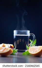 There Is A Glass Of Mulled Wine On The Table. Over A Glass Of Steam. Next To Lemons, Mint And An Apple. Selective Focus.