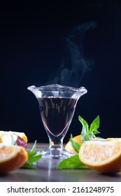 There Is A Glass Of Mulled Wine On The Table. Over A Glass Of Steam. Next To Lemons, Mint And An Apple. Selective Focus.