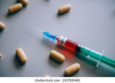 there is a green syringe with a blood sample on a light table to determine antibodies or create a vaccine against coronavirus, next to it are yellow antiviral pills