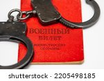There are handcuffs on the Russian military ID. Translation into Russian: Military ID, Ministry of Defense.Concept: mobilization into the army, criminal liability for desertion, evasion of war.