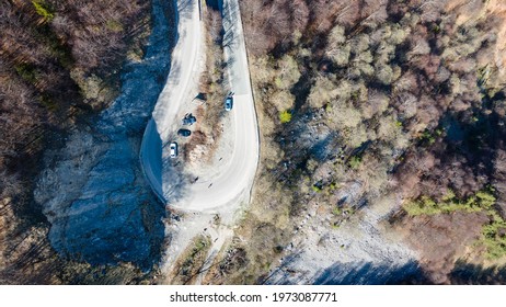 There Are Huge Snow Mountains And Long Winding Road In This Area. This Is A Great Place To Drive And Stop During A Road Trip. Travel On Hilly Road In Spring. Winding Road Aerial View By Drone.