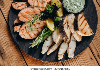 There Is A Interesting Dish With Lemon And Sauce In Front Of The Person In The Restaurant. It Looks Very Steamy And Tasty. We Can See A Lot Slices Of Fish And A Slice Of Lemon On The Plate.