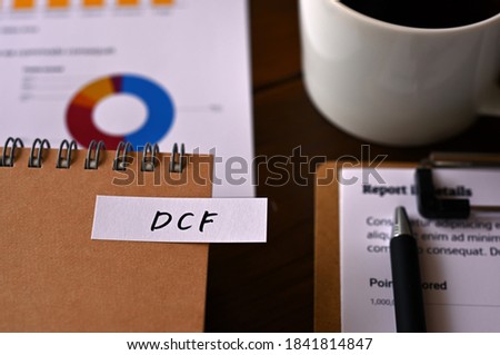 There is a laptop, a cup of coffee, and a sticky note with the word DCF written on it. It was an abbreviation for discounted cash flow.