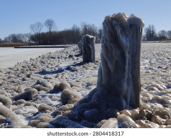 There is a large ice covered tree stump on the side of the road