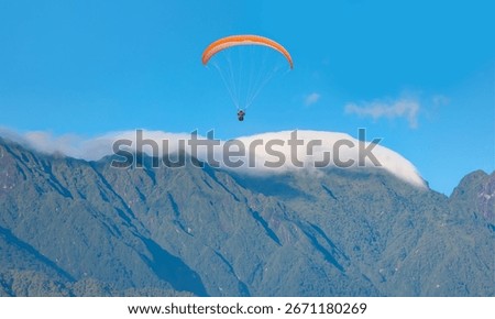 There is a large mountain range in the background with clouds covering the sky - Paraglider fly from Mount Babadag in Fethiye, Turkey