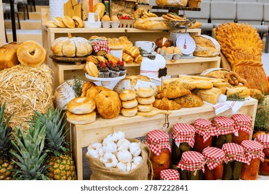 There is large table full of baked items jars of pickles at farm rural market event many foods are neatly arranged.