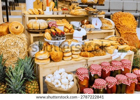 There is large table full of baked items jars of pickles at farm rural market event many foods are neatly arranged.