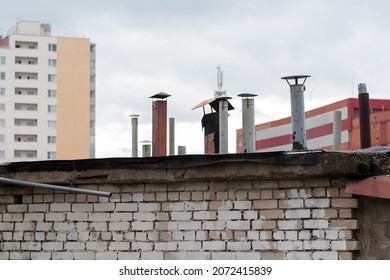 Il y a beaucoup de cheminées sur le toit d'un immeuble résidentiel.