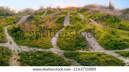 There are many different paths and directions through dangerous uneven terrain. Winding paths and routes on green hills
