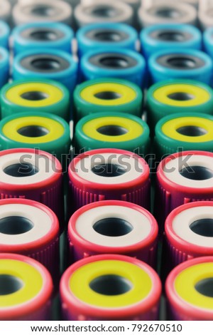 There are many Test Tubes with multicolor lids on the Test Tube rack. Macro photo with Test Tube for blood.