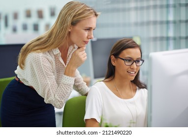 There Are No Stupid Questions. Shot Of Two Attractive Female Colleagues In A Quandary Over Some Work On A Computer In An Office Setting.