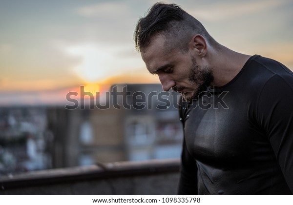 There is no
success without sweat. Young handsome man training hard and
sweating. Man doing sports outside on the bridge. Outdoors
recreation, stretching and training fit
body