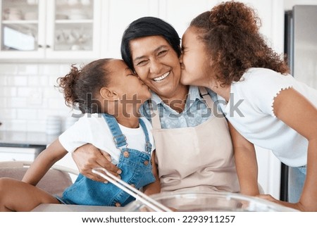 There are no sweeter smooches. Shot of two sisters kissing their grandmother while baking with her.