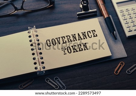 There is note book with the word Governance Token on a laptop. It is an eye-catching image.