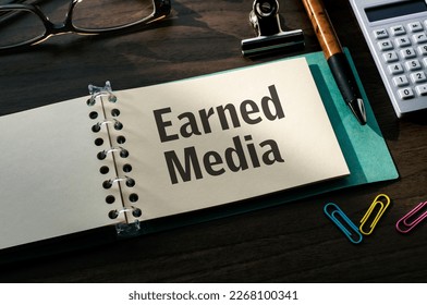 There is a notebook with the word Earned Media. It is eye-catching image.