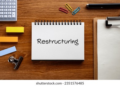 There is notebook with the word Restructuring. It is as an eye-catching image.