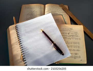 There is a pen on a blank page of the notebook. Notebook on top of open books. Place for your text. The concept of training, writing a scientific work, dissertation.