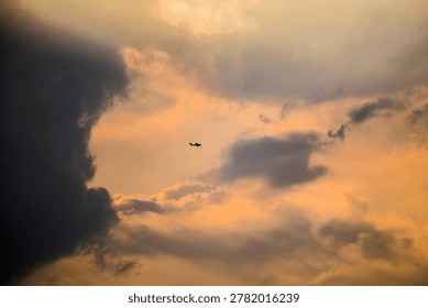There is a plane flying through the clouds at sunset.