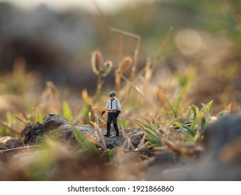 There Is PUBG Miniature Figure Toys Stand On Top Of The Rock And Blurred Grass As A Background.