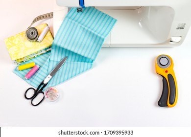 There Are Quilting Tools On The Table. Patchwork Knife, Scissors, Lined Cutting Mat, Self-locking, Threads, Measuring Tape, Sewing Machine. Copy Space