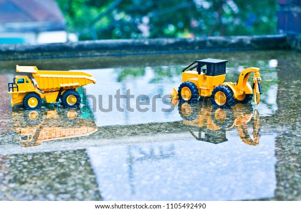 There are red brick pillars and truck\
and bulldozer on the cement floor that is\
submerged.