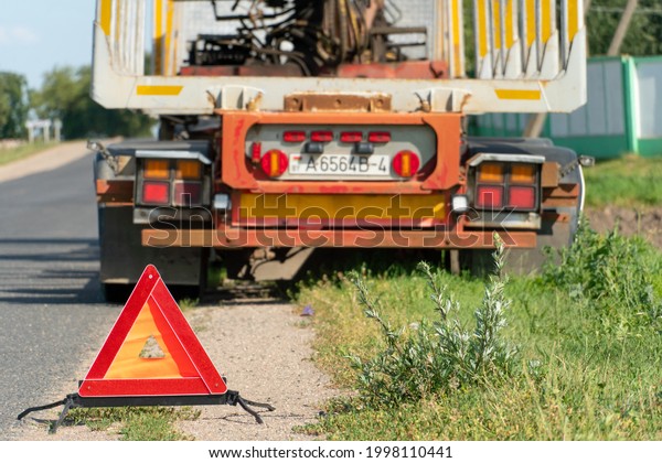 There is a red emergency stop sign on the\
side of the road. An accident on the road involving a truck. Cargo\
transportation and related risks at\
work.