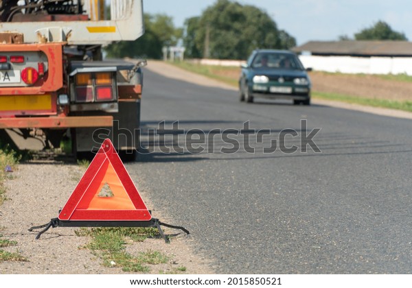 There is a red emergency stop sign on the\
side of the road. An accident on the road involving a truck. Cargo\
transportation and related risks at\
work.