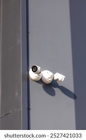 There is a security camera mounted on the side of a large building that overlooks the area for surveillance purposes
