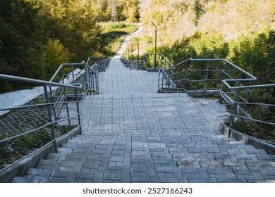 There is a set of wooden stairs that leads up to a beautiful forest, and it features a sturdy metal railing along the side for safety and support as you walk upwards into the lush greenery - Powered by Shutterstock