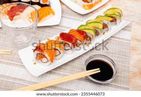 There are several narrow plates of boats with set of uramaki rolls on table. Traditional Japanese food, snack for small group of friends Stock photo © 