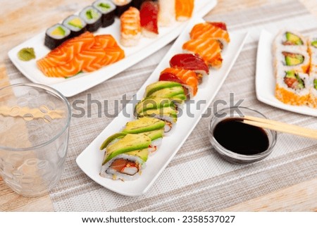 There are several narrow plates of boats with set of uramaki rolls on table. Traditional Japanese food, snack for small group of friends Stock photo © 